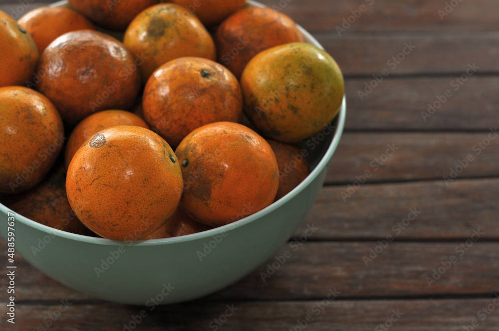 Closeup of ripe Tangerine, Mandarin, Oranges in a bowl, on a wood table Closeup of ripe Tangerine, Mandarin, Oranges in a bowl, on a wood table