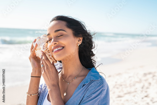 Fotobehang Young woman listening the sound of the ocean with a seashell