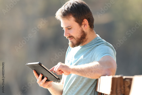 Serious man using tablet sitting in a garden