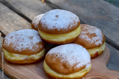 Sweet buns decorated with powdered sugar lie on a wooden table.