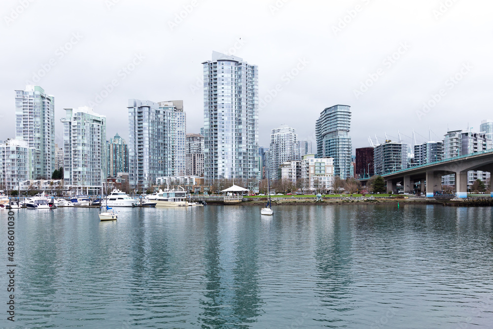 The Cambie Bridge, boats and modern glass and steel skyscrapers in the downtown area seen from the opposite banks during an overcast day, Vancouver, British Columbia, Canada
