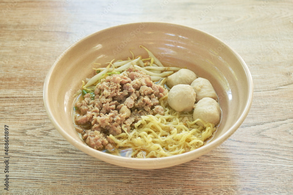Chinese egg yellow noodles topping boiled chop pork and ball in soup on bowl