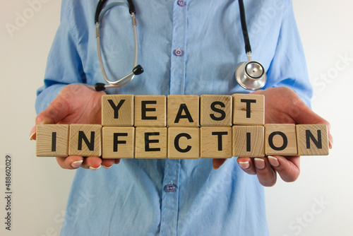 Female doctor holding text yeast infection from wooden blocks