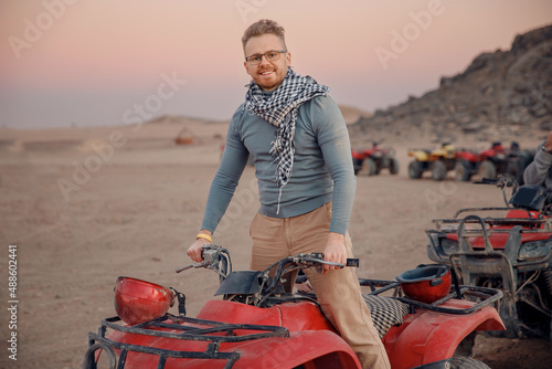 Man tourist with arafatka on quad bike ATV safari in desert Arab Emirates, Egypt photo