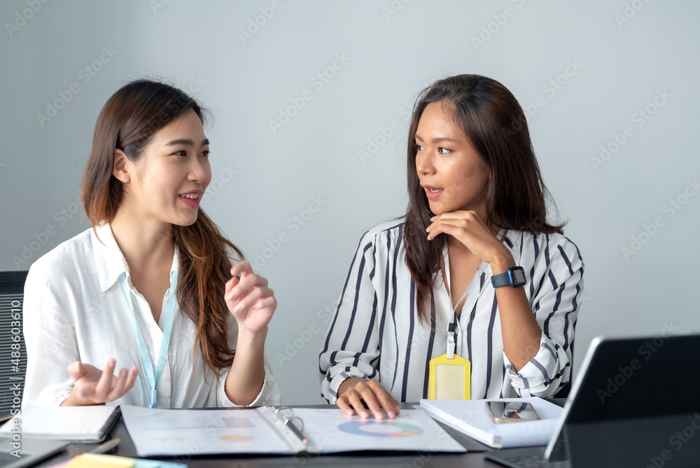 Two Smiling young Asian businesswoman talking to colleague, employees brainstorming, sitting working at office Two Smiling young Asian businesswoman talking to colleague, employees brainstorming, sitting working at office