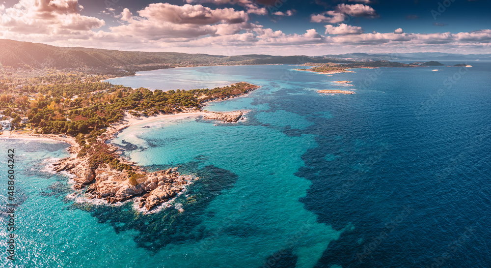 Aerial view of the paradise seashore with various shades of turquoise water. Coral reefs at depth and secluded sandy beaches in the resort village of Vourvourou in Greece Aerial view of the paradise seashore with various shades of turquoise water. Coral reefs at depth and secluded sandy beaches in the resort village of Vourvourou in Greece