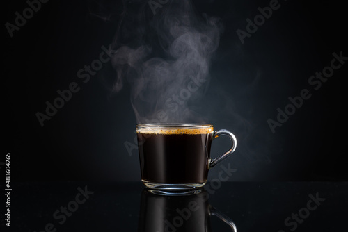 hot steaming fragrant coffee with steam, smoke in a transparent glass cup on a dark background