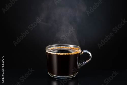 hot steaming fragrant coffee with steam, smoke in a transparent glass cup on a dark background