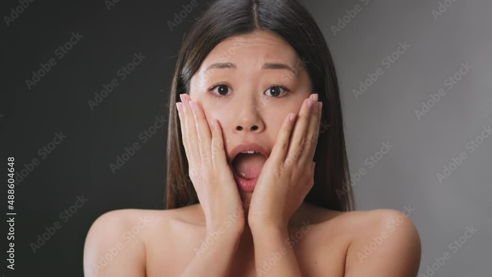Portrait of young amazed asian woman feeling shock and disbelief, opening mouth and touching her cheeks in disbelief Portrait of young amazed asian woman feeling shock and disbelief, opening mouth and touching her cheeks in disbelief