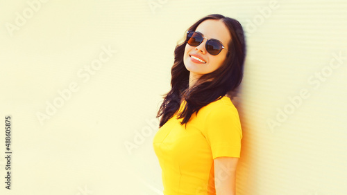 Portrait of beautiful brunette young woman wearing yellow dress on city street background