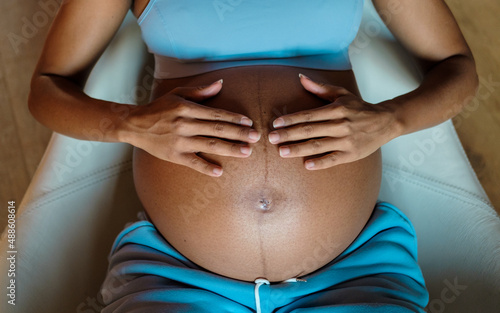Pregnancy concept. Detail of pregnant woman hands touching her belly.