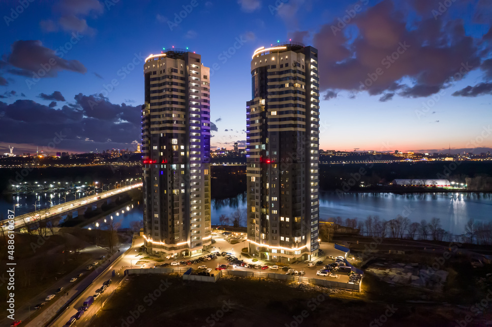 Fototapeta premium Tall buildings near the river at night in Kyiv.