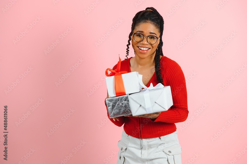Photo portrait of excited woman holding gift box in two hands isolated on pastel pink colored background Photo portrait of excited woman holding gift box in two hands isolated on pastel pink colored background