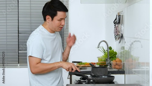 Stressed young man cooking and preparing food in the kitchen at home