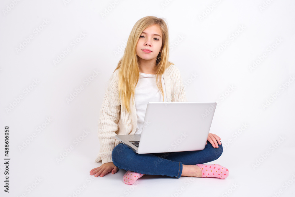 Happy caucasian teen girl sitting with laptop in lotus position on white background looking at camera with charming cute smile. Happy caucasian teen girl sitting with laptop in lotus position on white background looking at camera with charming cute smile.
