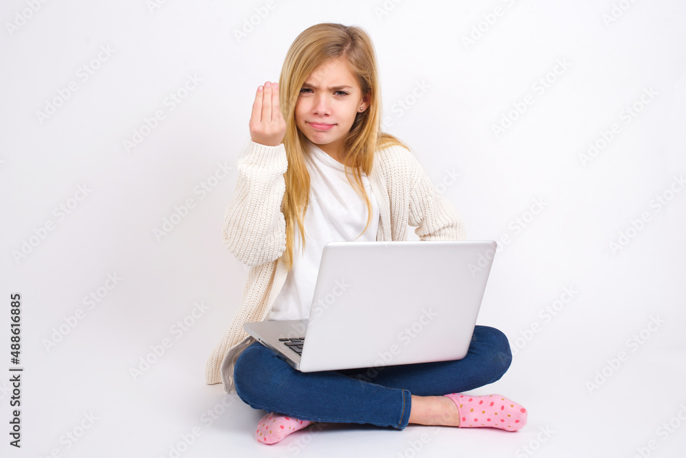 What the hell are you talking about. Shot of frustrated caucasian teen girl sitting with laptop in lotus position on white gesturing with raised hand doing Italian gesture, frowning, being displeased. What the hell are you talking about. Shot of frustrated caucasian teen girl sitting with laptop in lotus position on white gesturing with raised hand doing Italian gesture, frowning, being displeased.