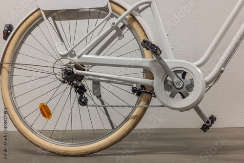 Close up view of back wheel of white bicycle with protection for clothes on chain. Sweden. 