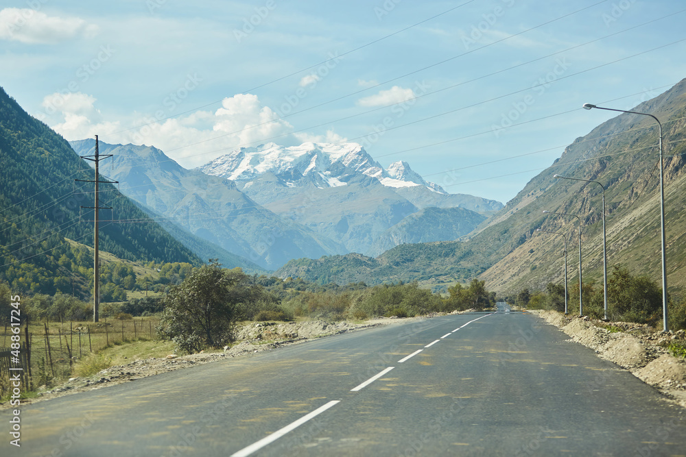 Fototapeta premium An asphalt road or highway without transport going into the distance to the mountains. The concept of travel and adventure.