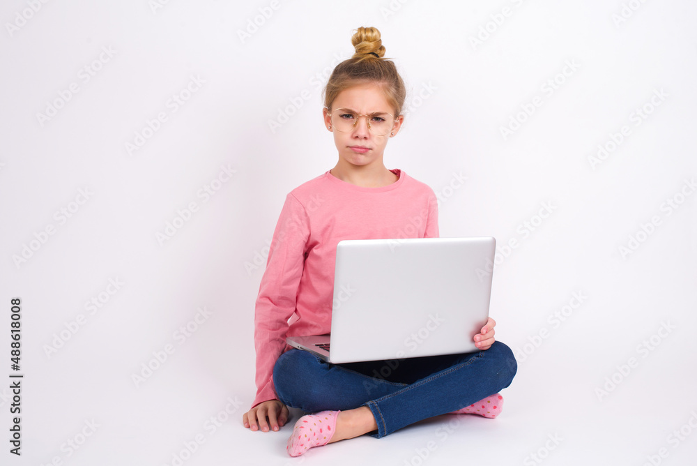 caucasian teen girl sitting with laptop in lotus position on white background Pointing down with fingers showing advertisement, surprised face and open mouth caucasian teen girl sitting with laptop in lotus position on white background Pointing down with fingers showing advertisement, surprised face and open mouth
