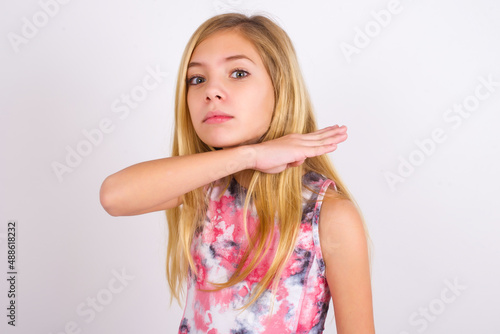 Slika na platnu little caucasian kid girl wearing sport clothing over white background cutting throat with hand as knife, threaten aggression with furious violence