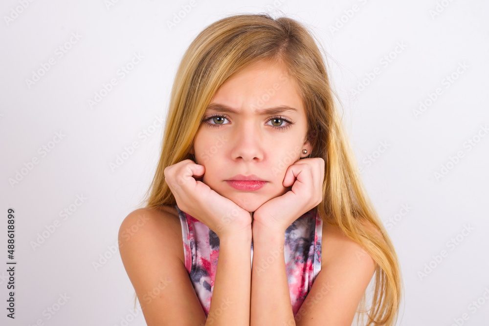 Portrait of sad little caucasian kid girl wearing sport clothing over white background hands face Portrait of sad little caucasian kid girl wearing sport clothing over white background hands face