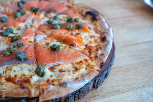 Homemade Smoked Salmon Pizza Topped with Capers  herbs  Dill  Cream Cheese  Tomato sauce and Cracked Peppers  close-up shot . The flatbread with fresh cheese.