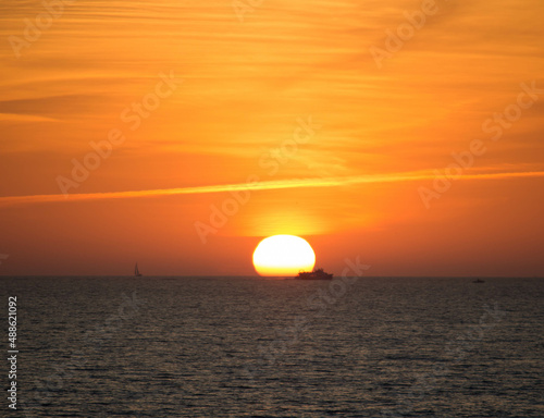 Fototapeta Naklejka Na Ścianę i Meble -  Puesta de sol en alta mar. Pesquero, y barco de vela.
