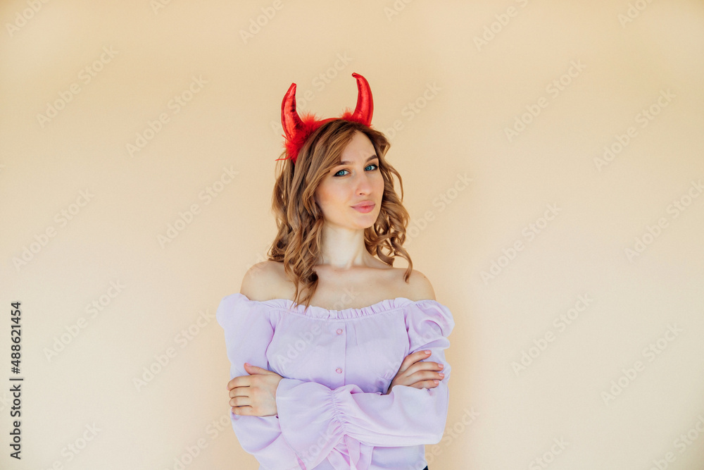 Portrait of a girl with wavy hair. The devil has red horns on his head. Playful mood, the girl smiles. Portrait of a girl with wavy hair. The devil has red horns on his head. Playful mood, the girl smiles.