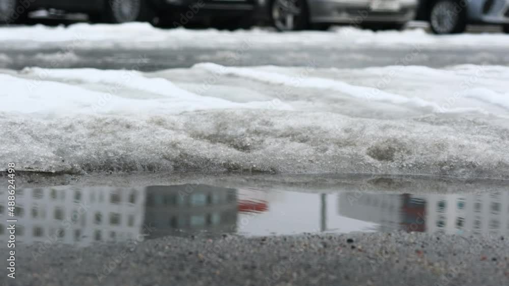 Large puddle of water on asphalt road against parking lot with cars standing in row at spring time outdoor Large puddle of water on asphalt road against parking lot with cars standing in row at spring time outdoor