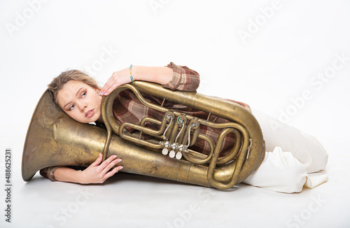 A beautiful girl lies with a musical wind instrument tuba