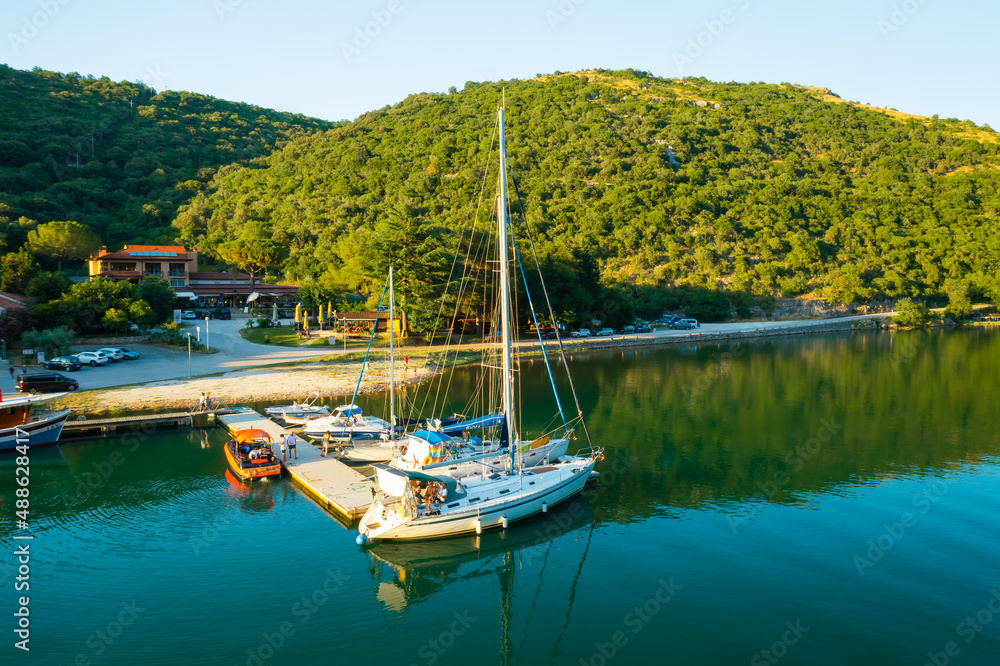 Luxurious yachts moored on marina near oyster farm surrounded by mountains covered with forests. Lim bay calm waters at sunset light. Aerial view