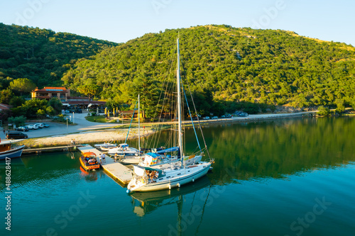 Luxurious yachts moored on marina near oyster farm surrounded by mountains covered with forests. Lim bay calm waters at sunset light. Aerial view