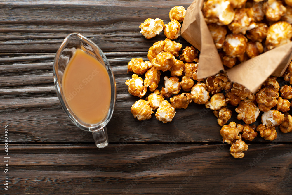 Caramelized popcorn in paper bag on wooden kitchen table flat lay