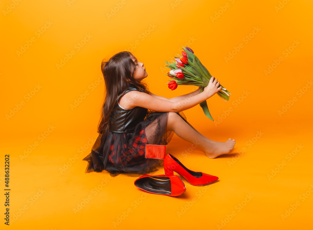 little girl smiles in a dress and big red shoes, holds a bouquet of ...