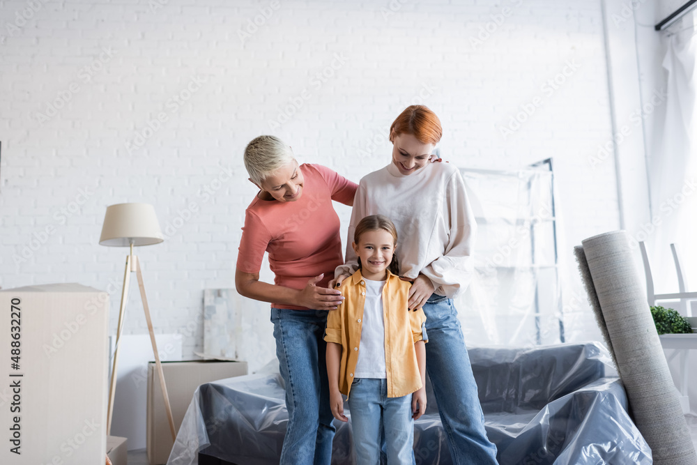 preteen sex happy preteen girl smiling at camera near same sex parents in new apartment Stock 写真 | Adobe Stock