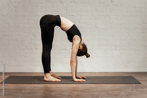 Young woman doing stretch exercise standing forward bend pose. Uttanasana 