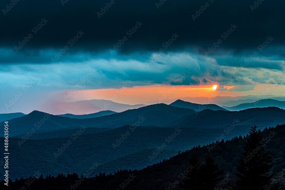 The sun barely peaks out of the clouds before setting over the Blue Ridge Mountains
