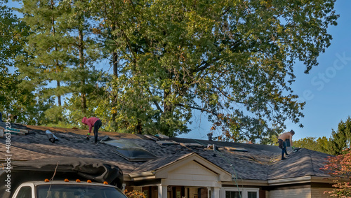 Roofers removing old material from a house in preparation for storm damage repair