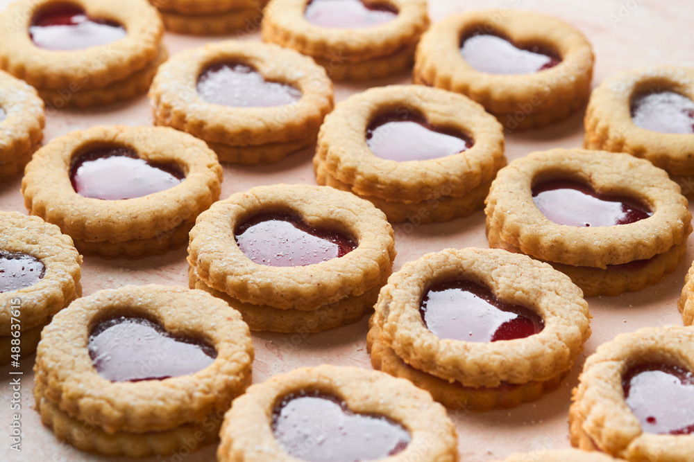 Traditional Linzer cookie with strawberry jam and powder sugar on pink beautiful background. Top view. Traditional homemade Austrian sweet dessert food on Valentines Day. Holiday snack concept.