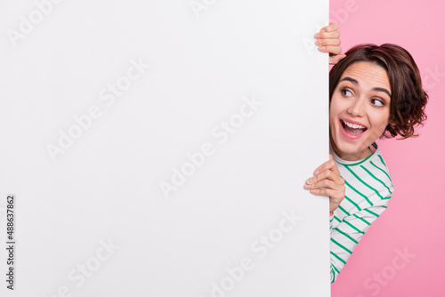 Portrait of attractive amazed cheerful girly girl holding large copy space poster ad look idea isolated over pink pastel color background