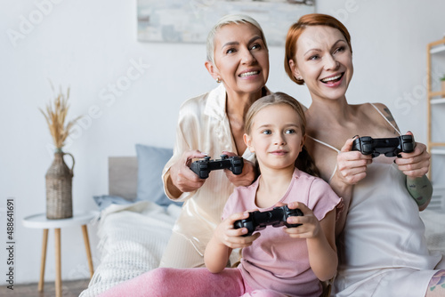 KYIV, UKRAINE - DECEMBER 8, 2021: Kid playing video game with mothers in bedroom © LIGHTFIELD STUDIOS