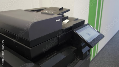 Young man copies documents on a copying system in office
