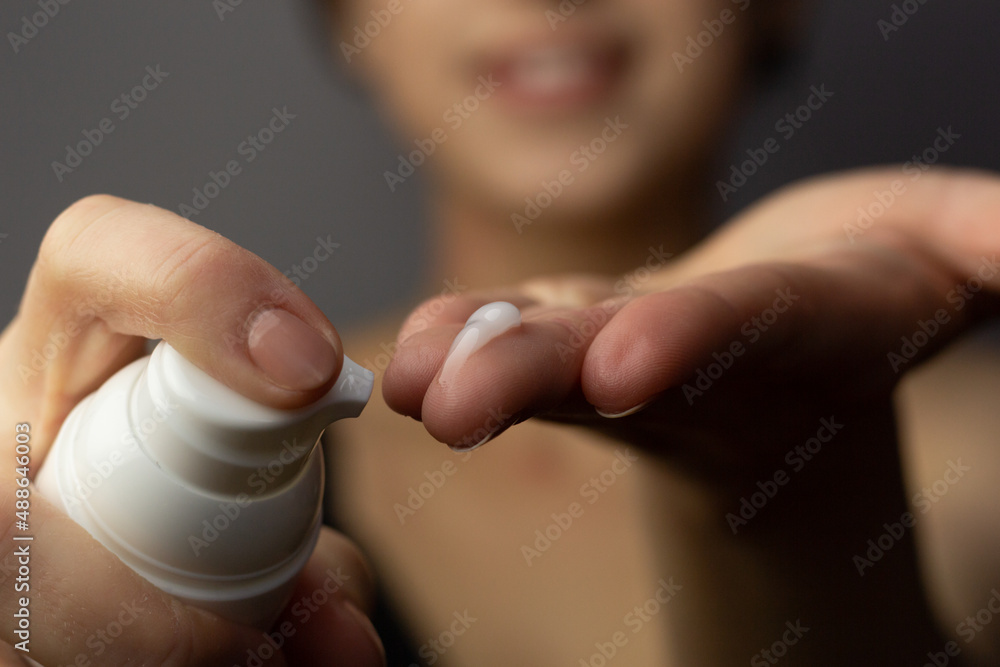 Closeup of a young woman applying prescription retinoid to her face.