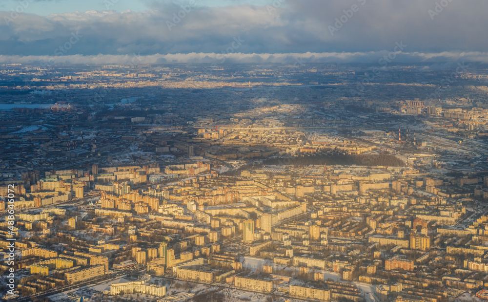 Aerial view of the city of St. Petersburg. Top view of residential city blocks. In the distance is the historical center of the city. Winter cityscape. Cloudy weather. Saint-Petersburg, Russia.