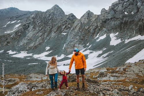Parents and child hiking in mountains family vacations travel outdoor adventure active healthy lifestyle man and woman with daughter holding hands walking together