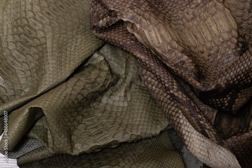 brown khaki dyed folded natural genuine python leather on the wooden table 