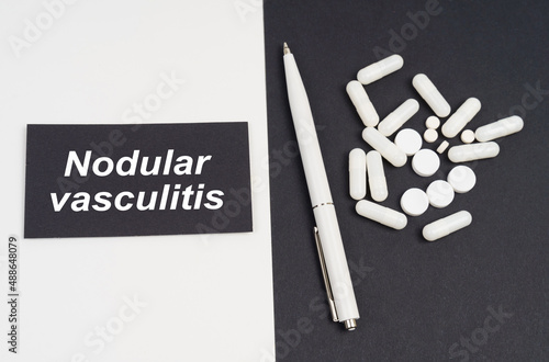 On a white and black surface are pills, a pen and a sign with the inscription - Nodular vasculitis photo