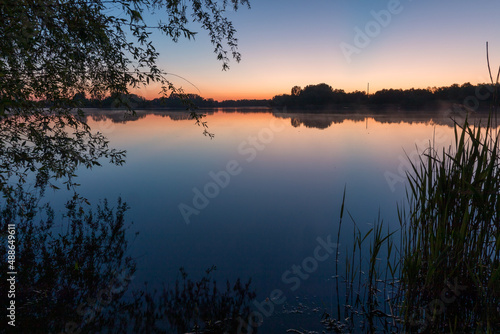 Sunset at the lake. Framed by trees and bushes. reflections in the water. Giftener See in Sarstedt near Hildesheim photo