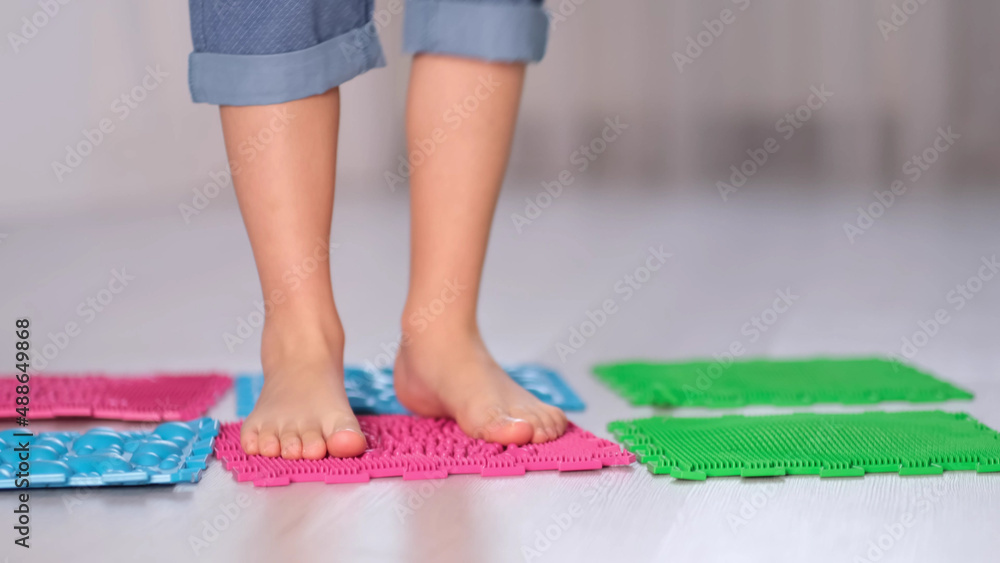 Little boy steps on orthopedic massage mats with different stiffness