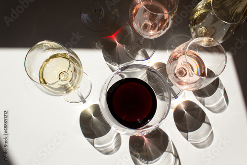 red and rose wine into glasses on white table with dark shadow top view	